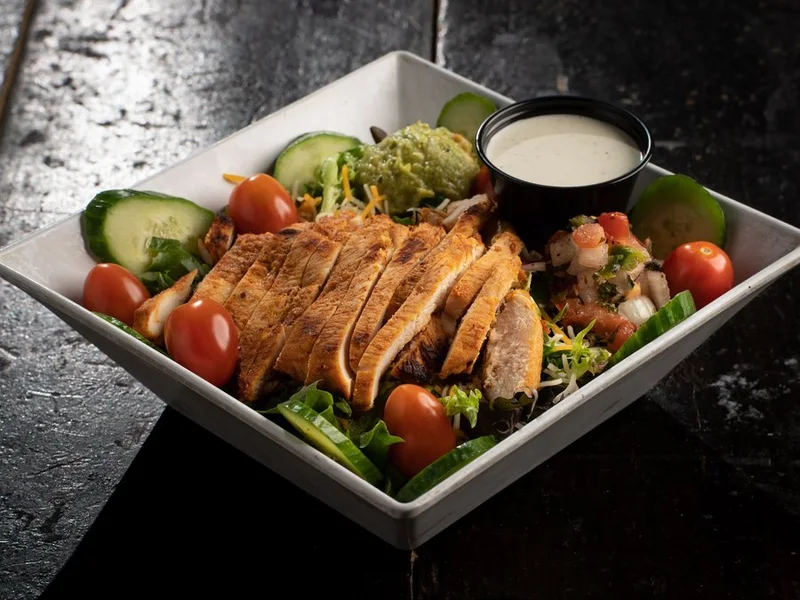 Fajita salad with guacamole, pico and grilled chicken over mixed greens
