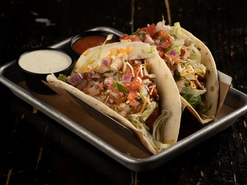 Buffalo chicken tacos with lettuce, shredded cheese and pico