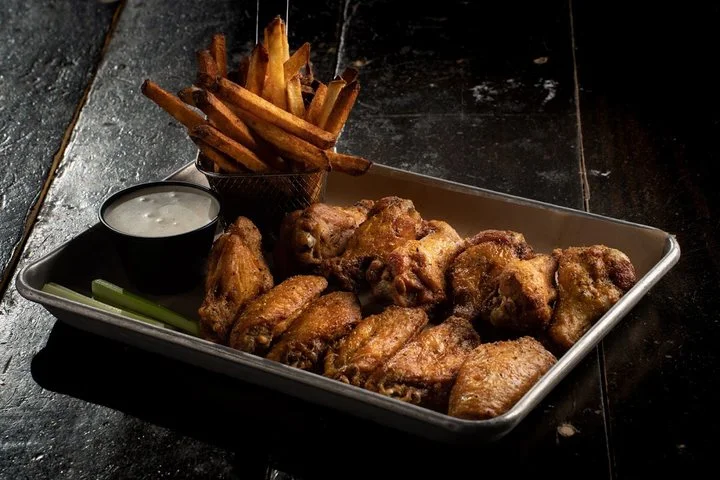A tray of bone-in wings with fries, ranch and celery